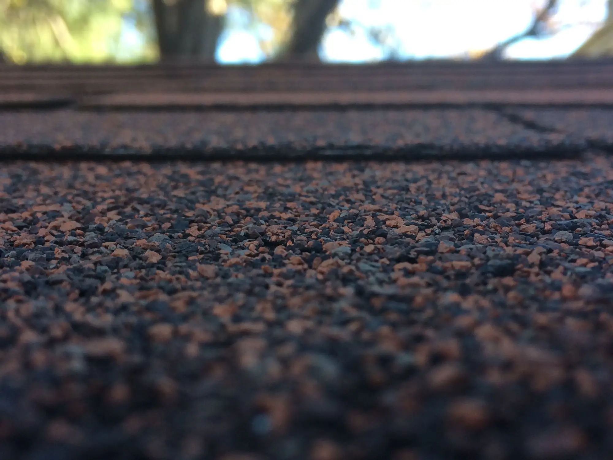 Close view of asphalt shingle granules along a roof course